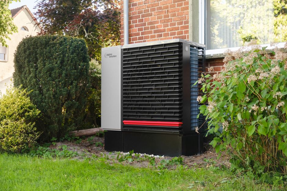 Pompe à chaleur installée dans le jardin, contre la façade d'une maison